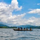Paddling a dugout canoe across calm lake waters, Uganda