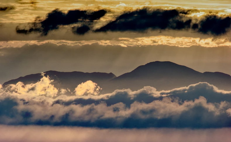 Golden clouds above a mountain silhouette and the sea