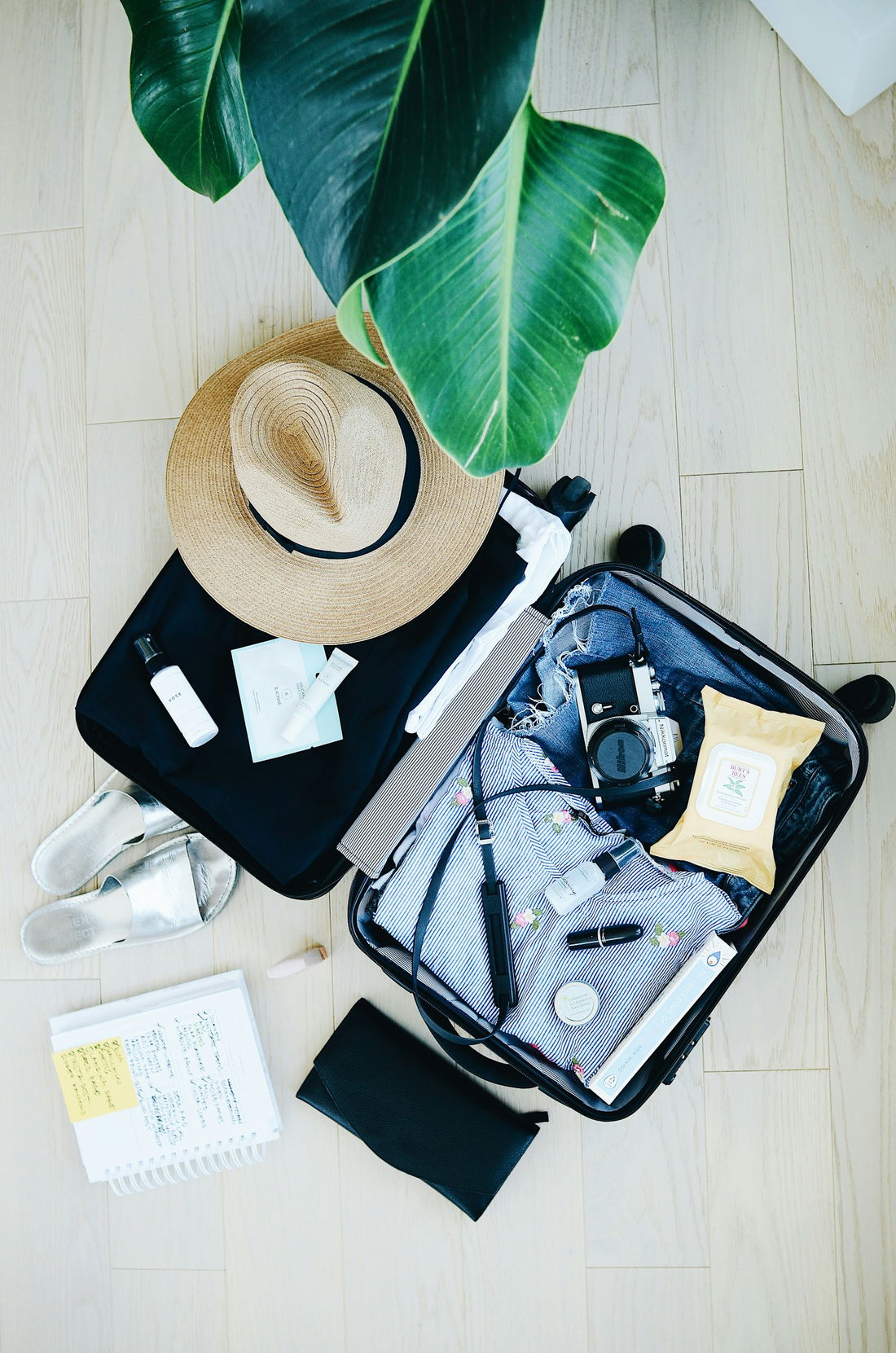 Open suitcase packed with travel essentials, hat and camera for a Cape Town trip