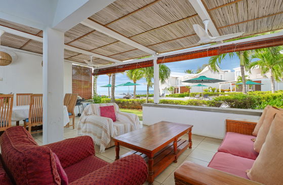 Covered patio with red-cushioned seating overlooking ocean