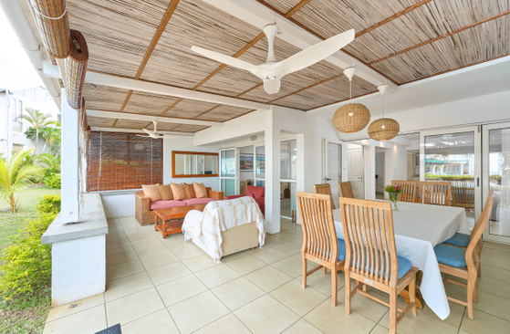 Dining area with rustic wood furniture under thatched roof