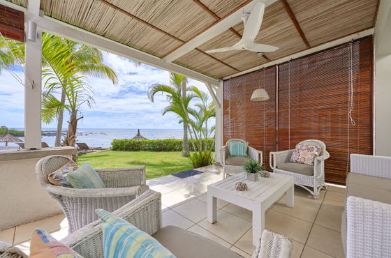 Outdoor dining set under veranda next to white sofa