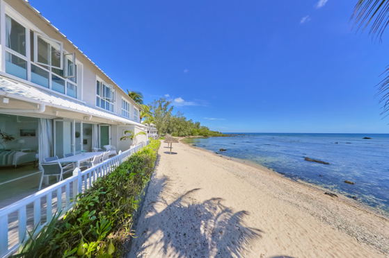 Beachfront view of villa with white railing and sandy path