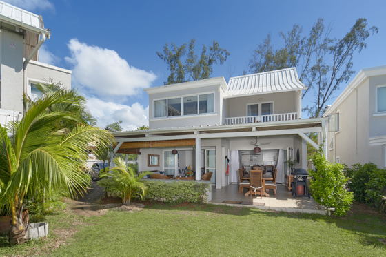 Exterior view of two-story tropical villa with lush gardens