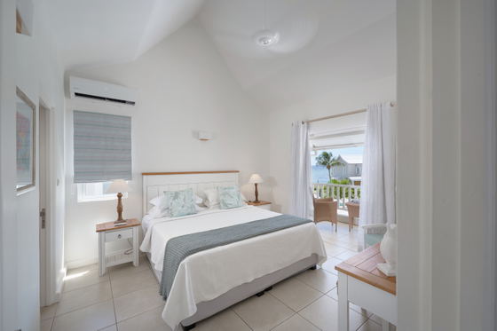 Queen bedroom with natural tones and sea views