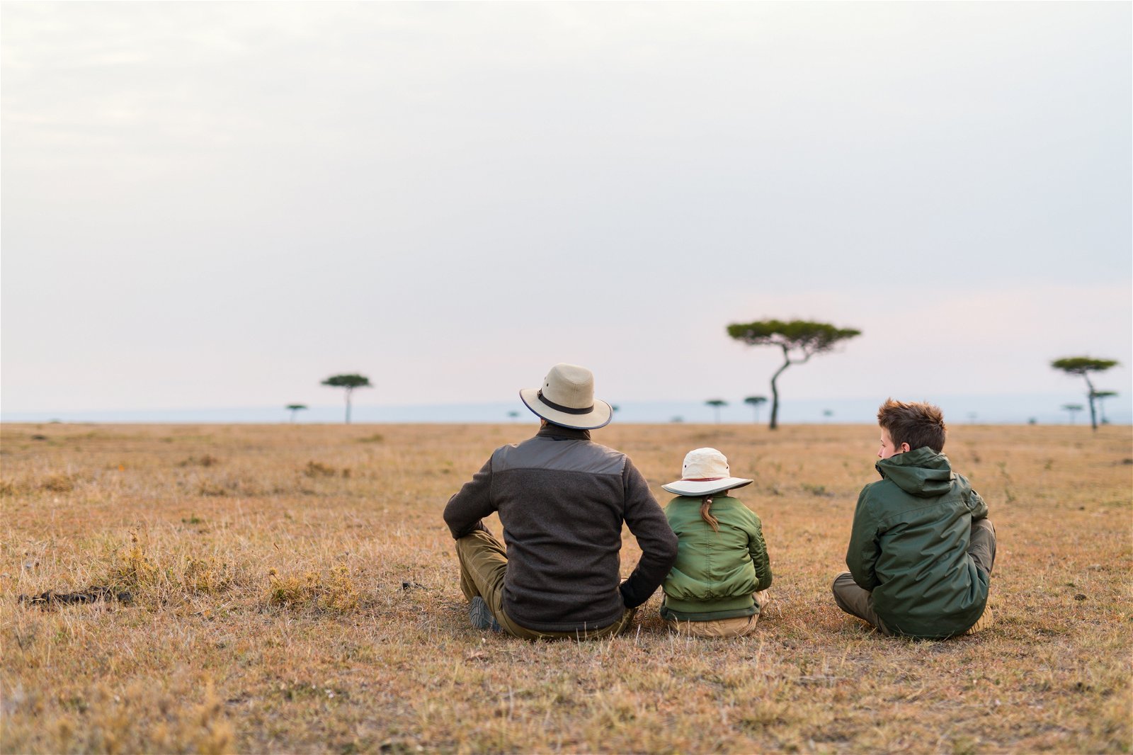 Father and two children on African savanna plains looking at the horizon