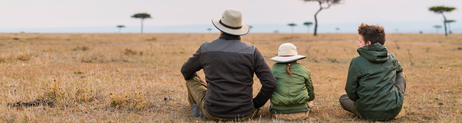 Father and two children on African savanna plains looking at the horizon