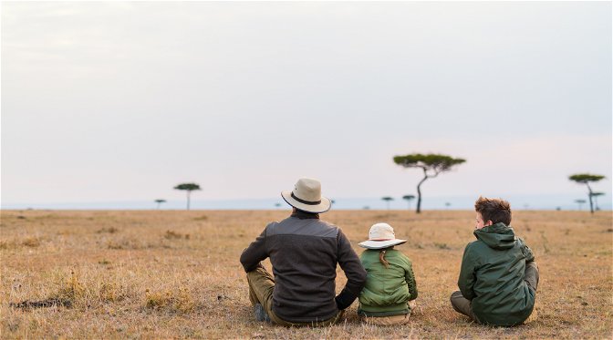 Father and two children on African savanna plains looking at the horizon