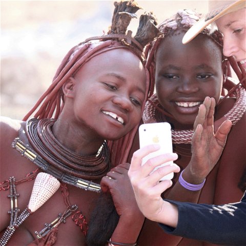 Himba woman and tourist sharing a moment in Namibia.