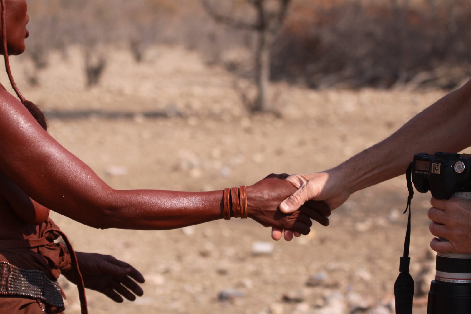 Himba woman and tourist shaking hands in Namibia