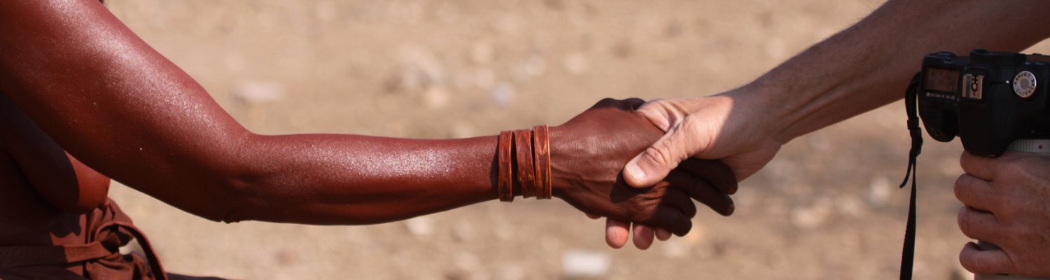Himba woman and tourist shaking hands in Namibia