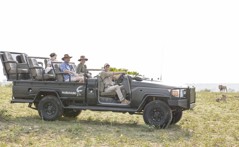Guests on safari at MalaMala Game Reserve observing lions
