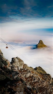 Cape Town's Table Mountain cable way and Lions Head visible under the mist.