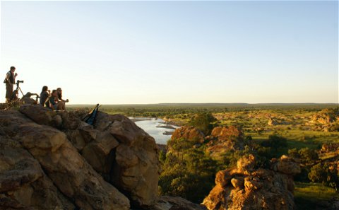 Group of tourists enjoying sundowner drinks in Masahatu Game reserve with the Matloutse River in the background.