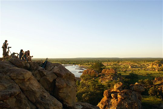 Group of tourists enjoying sundowner drinks in Masahatu Game reserve with the Matloutse River in the background.