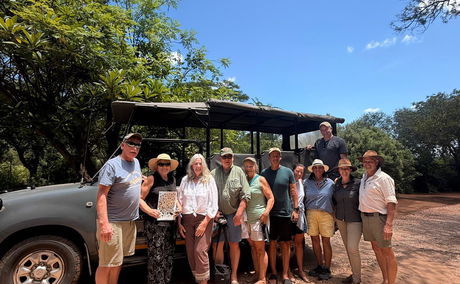 Group of guests in front of safari vehicle with safari guides
