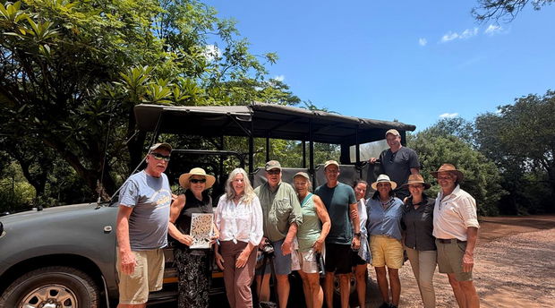 Group of guests in front of safari vehicle with safari guides
