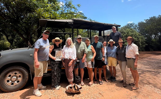 Group of guests in front of safari vehicle with safari guides