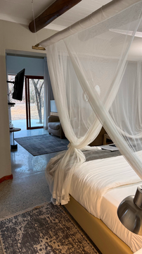 canopy-draped bed opens onto serene views of the wilderness. The blend of elegant interiors and natural surroundings creates a truly tranquil retreat.