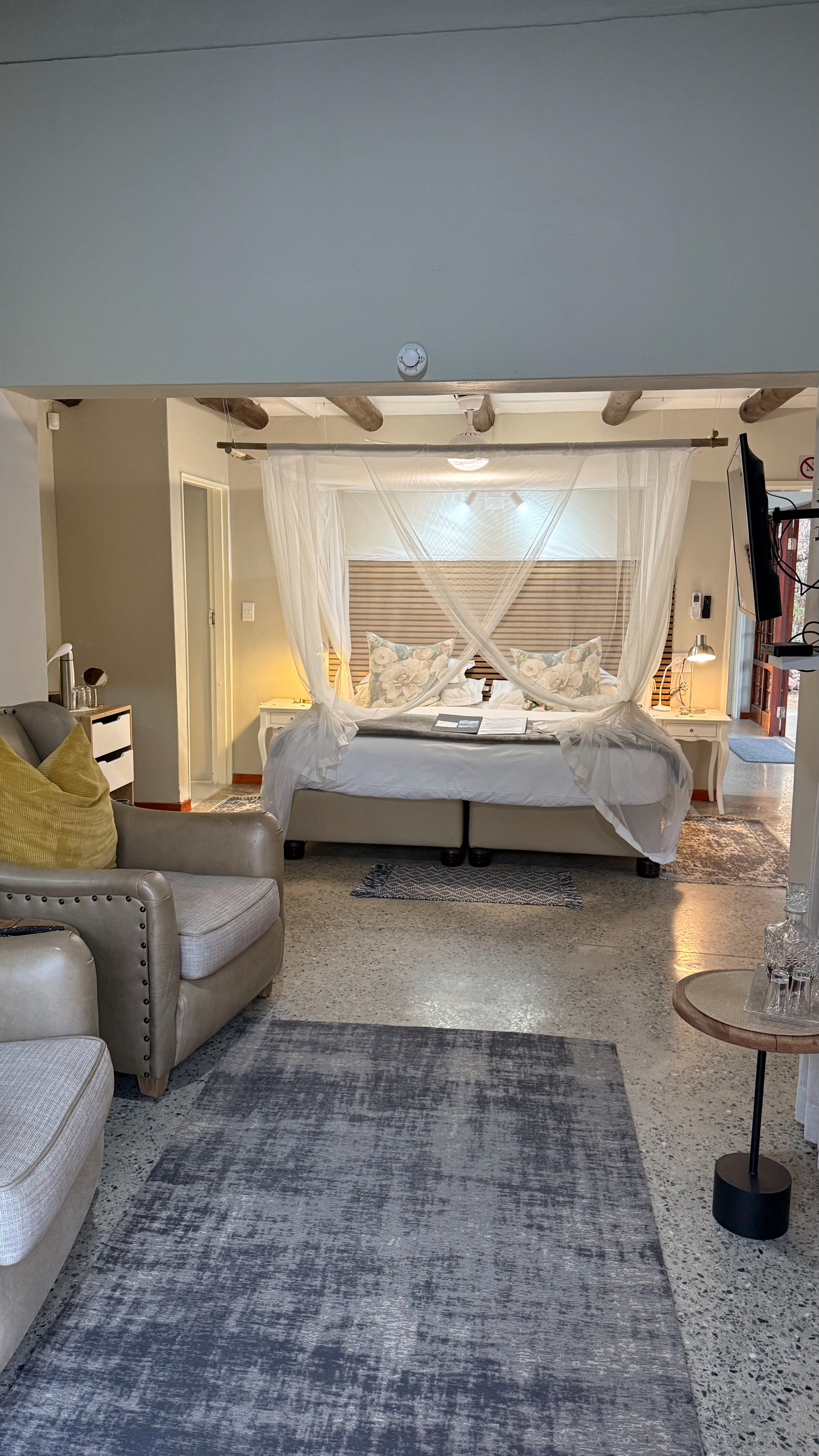 elegant suite where a canopy bed meets refined, cozy seating. The tasteful design and warm ambiance create a welcoming retreat for ultimate relaxation.
