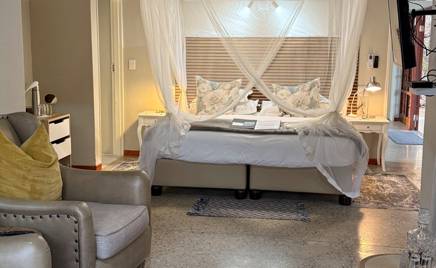 elegant suite where a canopy bed meets refined, cozy seating. The tasteful design and warm ambiance create a welcoming retreat for ultimate relaxation.