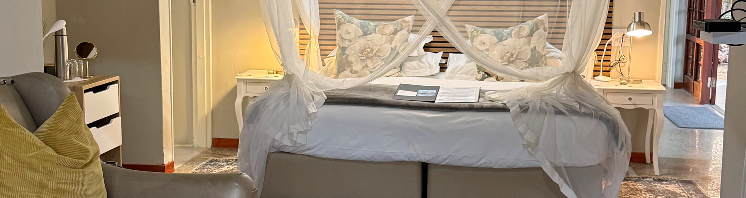 elegant suite where a canopy bed meets refined, cozy seating. The tasteful design and warm ambiance create a welcoming retreat for ultimate relaxation.