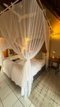 intimate retreat with a canopy-draped bed and warm ambient lighting. The elegant detailing creates a romantic and tranquil space, ideal for unwinding after a day of safari adventures.