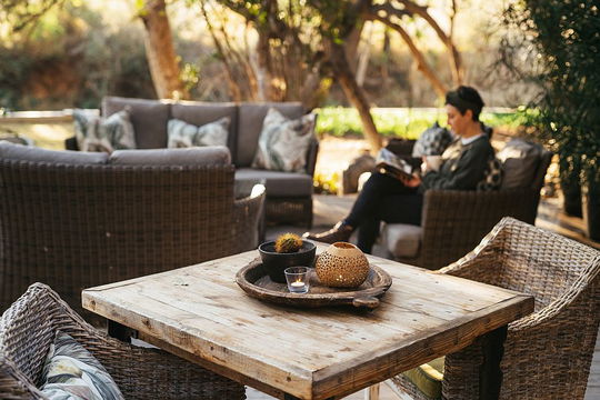 Simbavati Amani Lodge offers a cozy outdoor seating area surrounded by lush greenery, providing a relaxing space for guests to unwind.