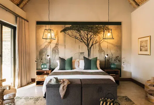 Simbavati Camp George offers stylish rooms with comfortable furnishings, including a table, plant, and decorative accents, creating a cozy and inviting atmosphere perfect for relaxation.