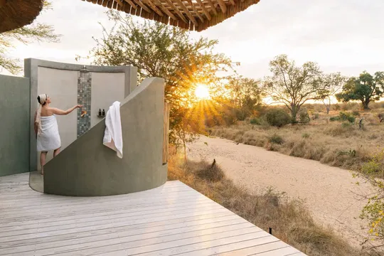 Simbavati Camp George offers a serene outdoor setting with a deck surrounded by nature, perfect for special occasions, where guests can enjoy the beauty of trees, plants, and clear skies.