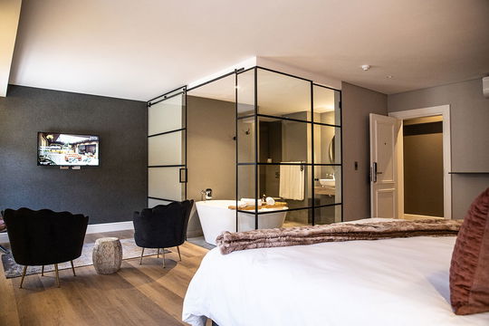 Indulge in the perfect blend of elegance and comfort at Hawthorn Boutique, featuring a spacious bedroom with a striking mirror and luxurious design.