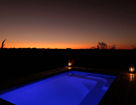 Unwind under the starry sky at Simbavati Mbubu Cottage, where the shimmering pool and peaceful surroundings create a perfect nighttime retreat.