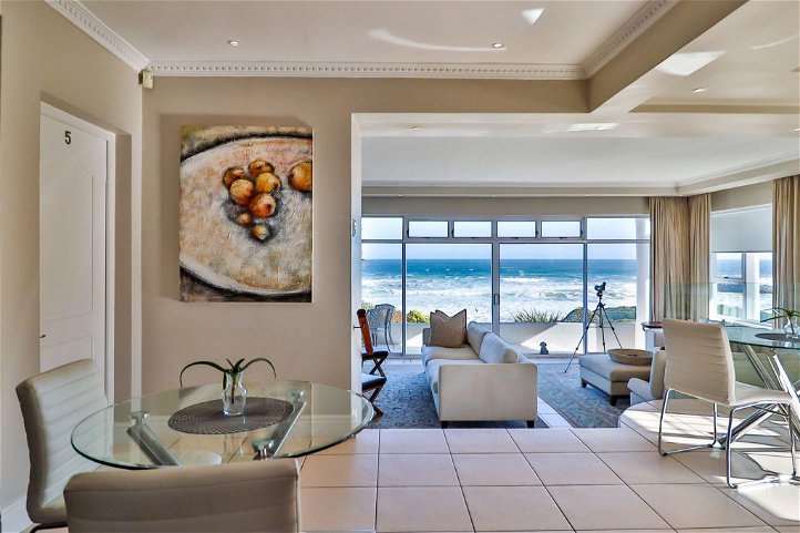 A modern lounge with ocean views white furniture and a telescope. Contemporary art on the wall