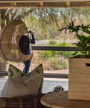 At Simbavati River Sands, the balcony offers a peaceful atmosphere, featuring cozy furniture and touches of nature.