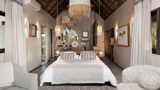 Relax in the spacious rooms at Simbavati Waterside, where stylish design meets comfort, featuring cozy beds and charming decor.