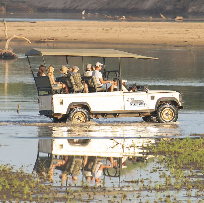 safari in a game drive car going through the luangwa river