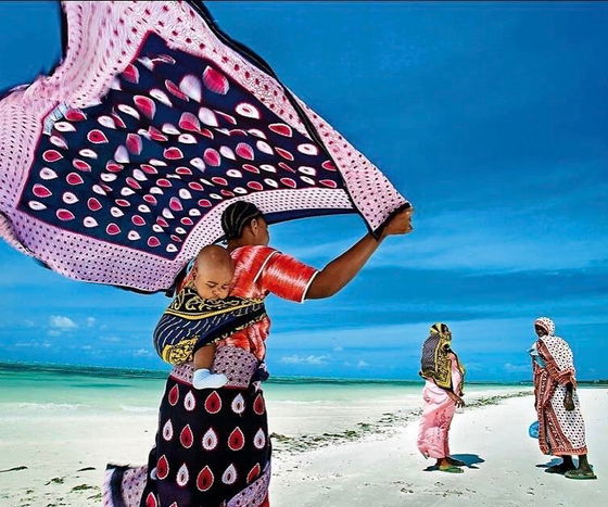 Embrace the vibrant spirit of Zanzibar at Imani Penthouse: women in colorful kangas on Kiwengwa Beach.