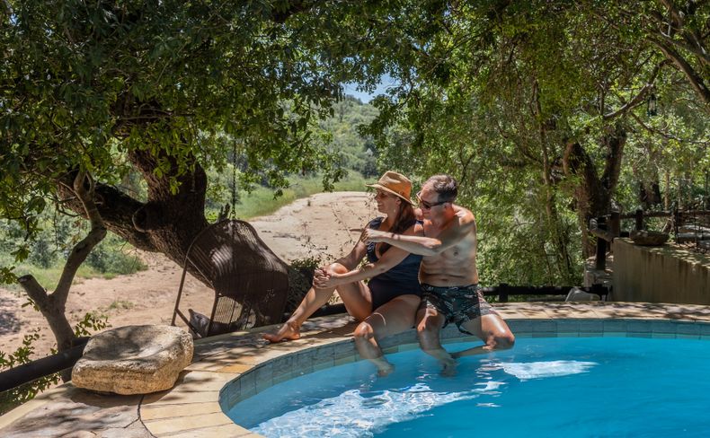 Honeymoon couple enjoying time at the Shimungwe Lodge pool with a view of the African bush