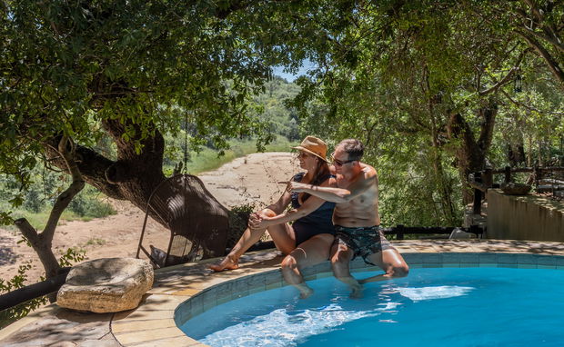 Honeymoon couple enjoying time at the Shimungwe Lodge pool with a view of the African bush