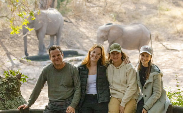 Family on safari in Africa watching elephants at a waterhole