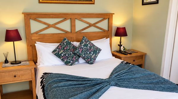Double bed with a wooden headboard and waterfall artwork in the Waterfall En Suite at Amberlight Guesthouse in Krugersdorp.