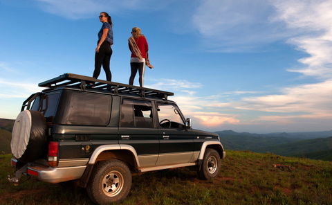 girls standing on a car on the top of a mountain in malawi enjoying the landscape