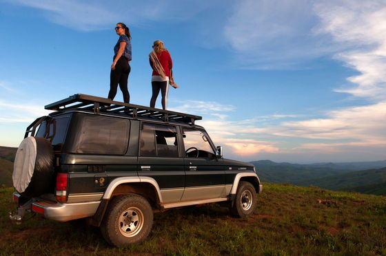 girls standing on a car on the top of a mountain in malawi enjoying the landscape