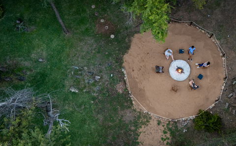 Ngoma Bush Lodge boma with seating arranged around a central fire pit, ambient lantern lighting, and a natural bushveld backdrop