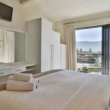 Wake up to breathtaking mountain views in our bright and airy bedroom, Enjoy luxury and natural light at Hermanus Luxury Accommodation by DCC Hotel Group,