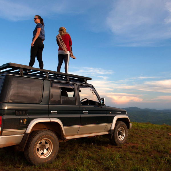 girls standing on a car on the top of a mountain in malawi enjoying the landscape