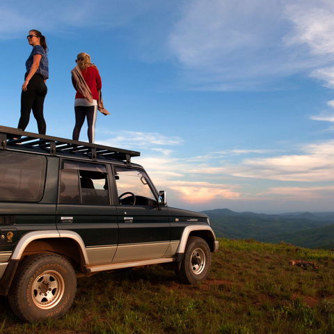 girls standing on a car on the top of a mountain in malawi enjoying the landscape