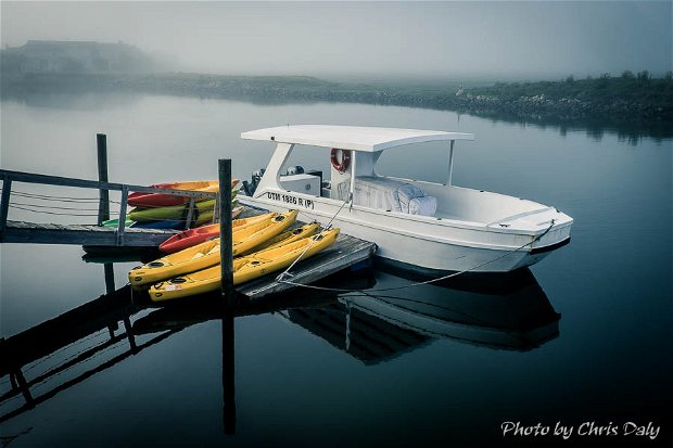 Boat and kayaks on Thesen Island in Knysna Lagoon on a misty morning.