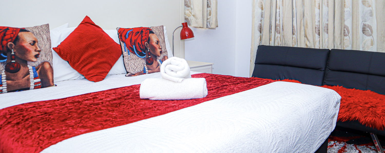 Image of a bed with rolled Lalakhona branded towels on it. 