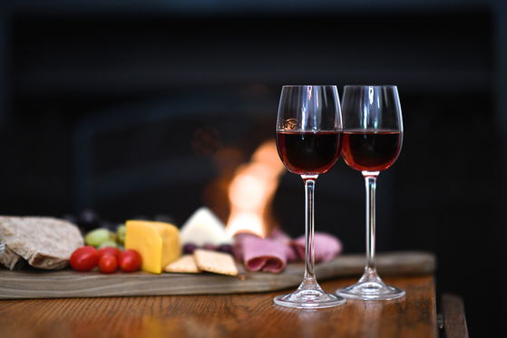 A warm and inviting scene at Bonne Esperance Guest House in Stellenbosch: two sherry glasses, a cheese board, and a roaring fireplace, perfect for winter evenings.